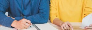 Man and Woman with Notebook and Calculator Working on Budget