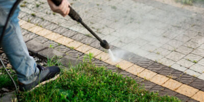 Close up photo of a man hands, cleans a tile of grass in his yard. High pressure cleaning